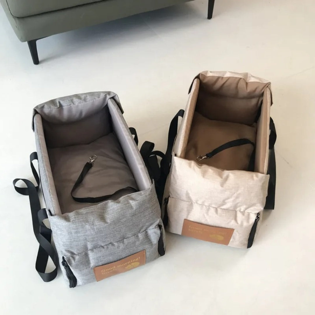 Zwei tragbare Babytragetaschen, grau und beige, mit Sicherheitsgurten auf weißem Boden.