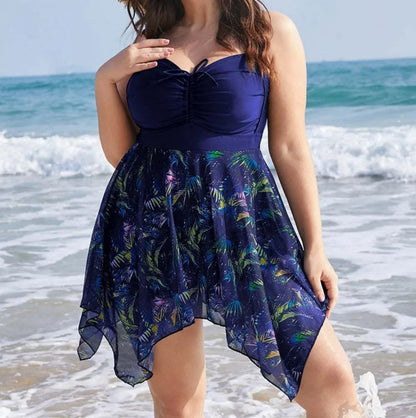 Frau im blauen Badeanzugkleid mit tropischem Muster am Strand, Sommermode, Plus-Size.