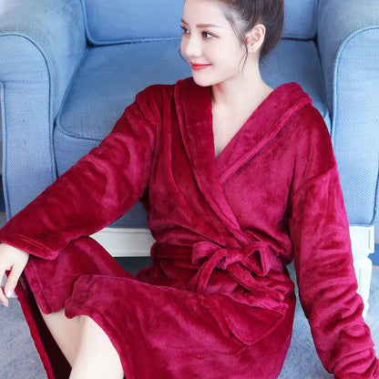 Frau in weinrotem Fleece-Bademantel auf blauem Sofa, gemütlich und stilvoll.
