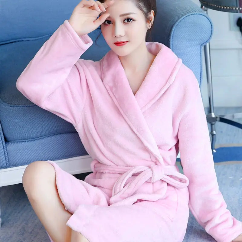 Frau im rosa Bademantel aus Fleece auf blauem Sofa, gemütlich, weich, Morgenmantel.