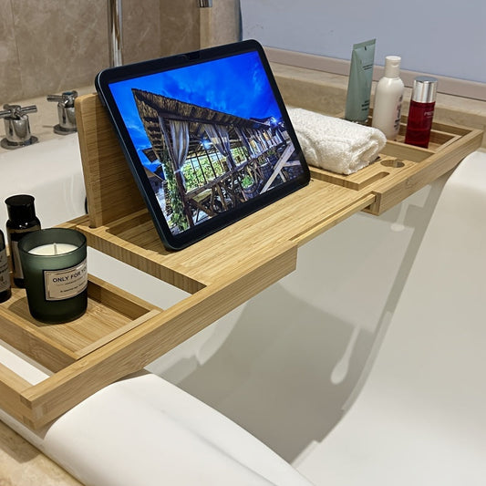 Bambus-Badewannenablage mit Tablet-Halter, Kerze, Handtuch und Pflegeprodukten im Badezimmer.
