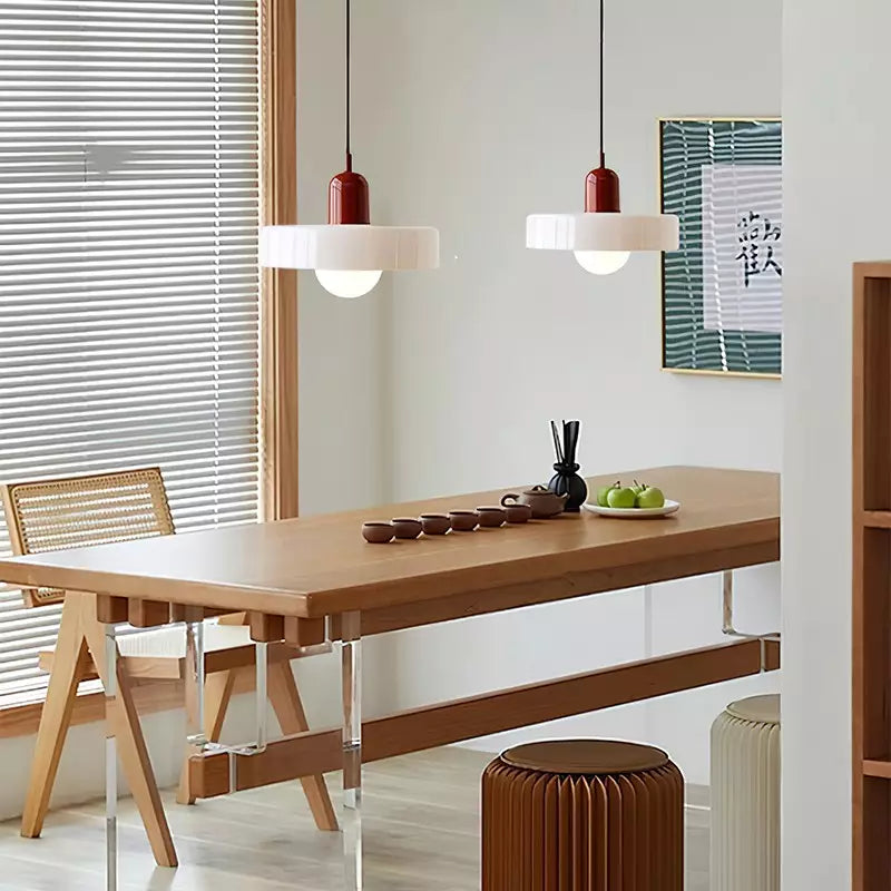 Moderne Pendelleuchte aus Glas und Metall über Esstisch, Bauhaus-Stil, rot-weiß, Esszimmerbeleuchtung.