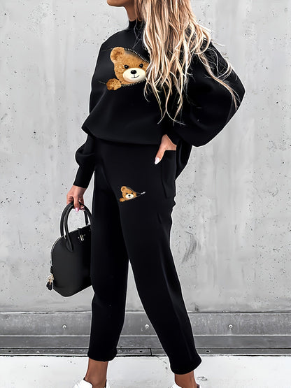 Frau in schwarzem Teddy-Print-Sweatshirt und Hose, hält schwarze Handtasche.