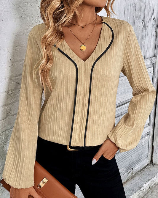 Beige Damenbluse mit V-Ausschnitt und schwarzen Akzenten, elegante Mode, langärmlig.