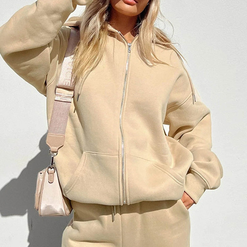 Frau in beigem Hoodie und Jogginghose, trägt beige Umhängetasche, Freizeitmode.