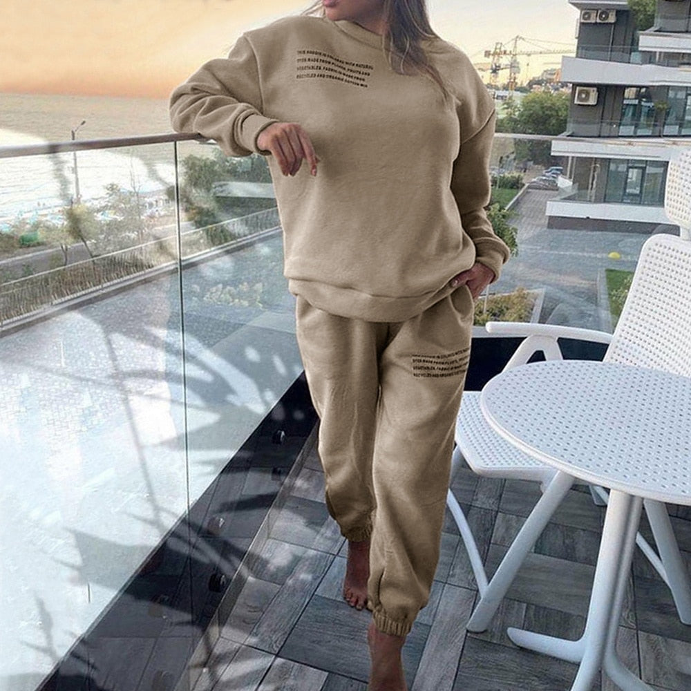 Frau in beigem Jogginganzug auf Balkon, Freizeitmode, gemütlich, urbaner Hintergrund, Sommer.