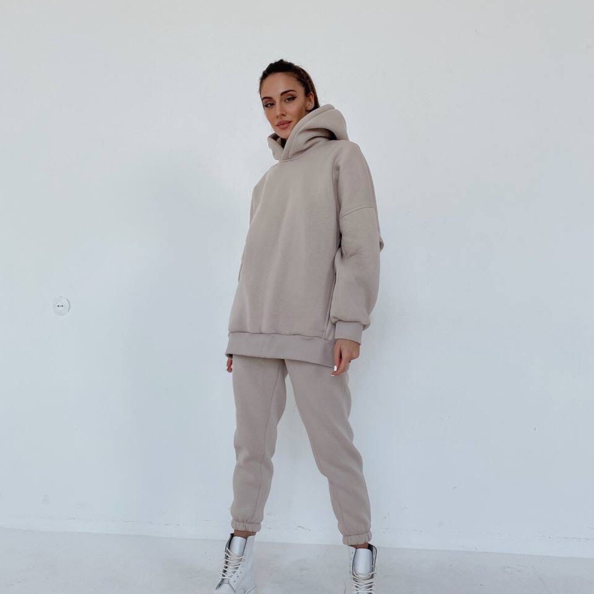 Frau in beigem Hoodie und Jogginghose, lässige Mode, gemütlicher Freizeitlook, weiße Sneaker.