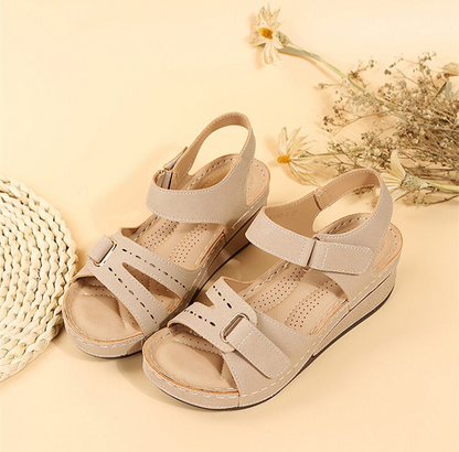 Beige Damen-Sandalen mit Keilabsatz, Leder, Sommerschuhe, bequem, modisch, Blumenhintergrund.