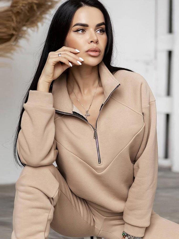 Frau in beigem Sweatshirt mit Reißverschluss, Freizeitmode, gemütlicher Look, Indoor-Aufnahme.