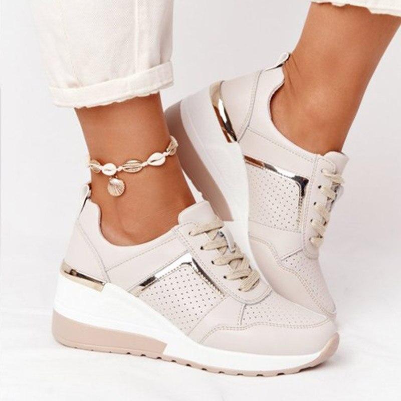 Beige Damen-Sneaker mit Keilabsatz, goldenen Details und Muschel-Fußkettchen, modisch und bequem.