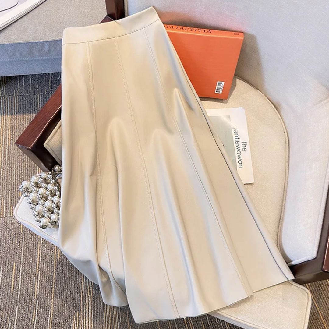 Beiger Lederrock, A-Linie, auf Sessel, elegantes Design, Damenmode, stilvoll, modern.