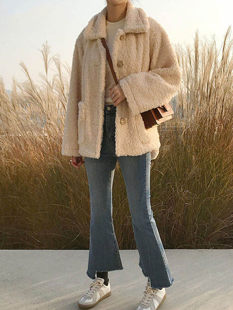 Frau in beiger Teddyjacke, Jeans und Sneakers im Freien, Herbstmode, lässiger Stil.