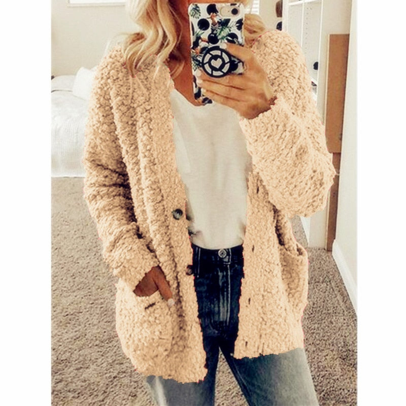 Frau trägt beige Strickjacke, weiße Bluse, Jeans; gemütliche Herbstmode, Damenbekleidung.