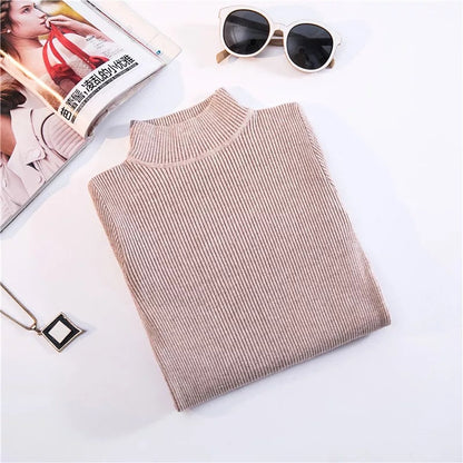 Beigefarbener Rollkragenpullover aus Strick, gefaltet, neben Sonnenbrille und Magazin.