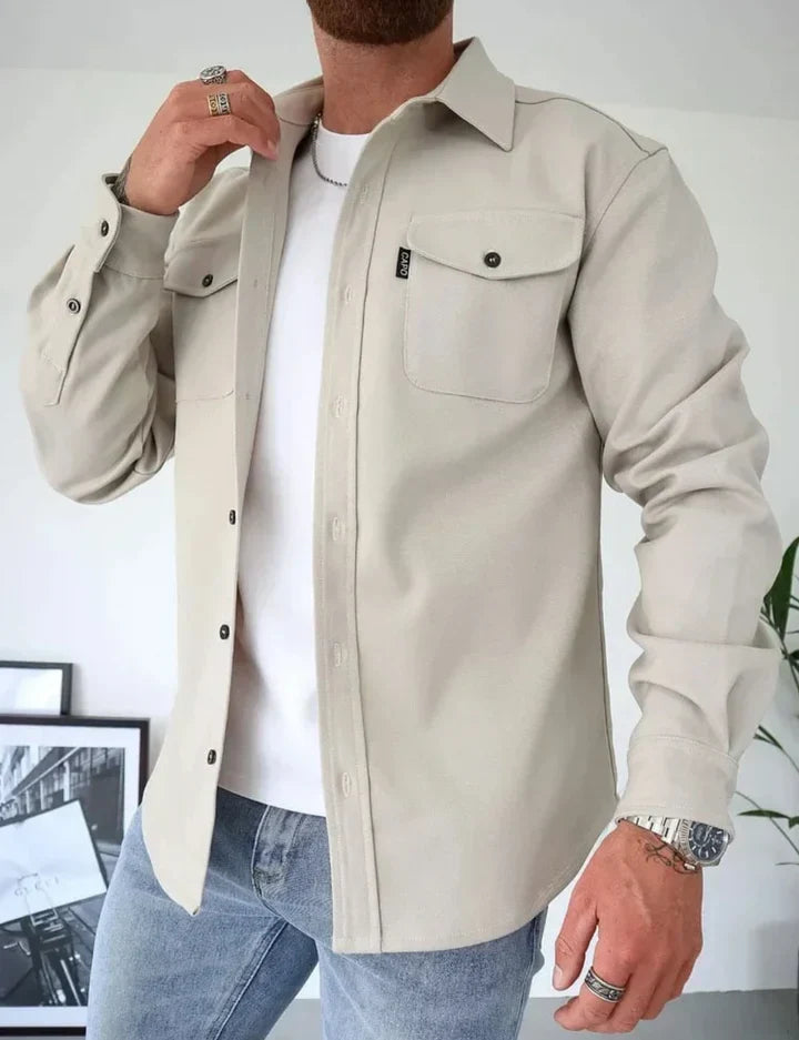 Mann in beiger Hemdjacke aus Baumwolle, weiße T-Shirt, blaue Jeans, lässiger Stil.