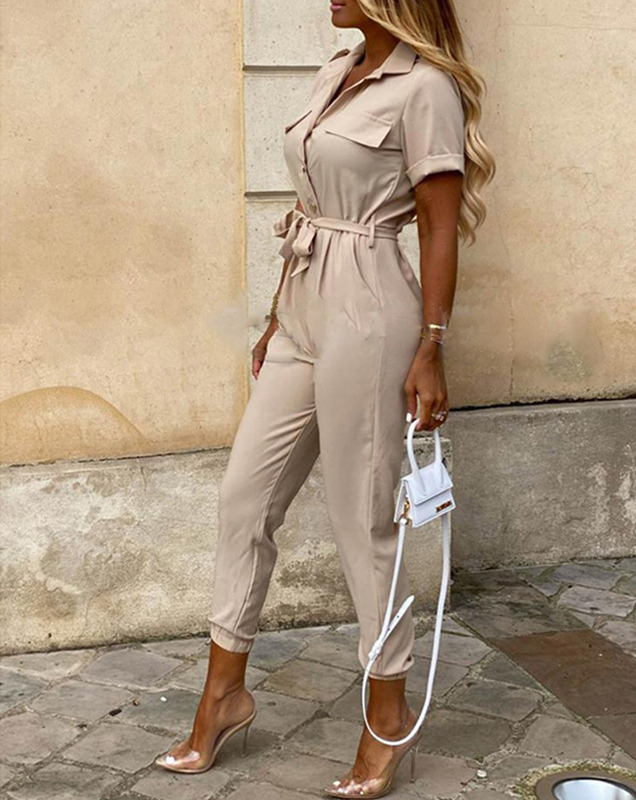 Frau in beige Jumpsuit mit Gürtel, transparenten High Heels und weißer Handtasche.
