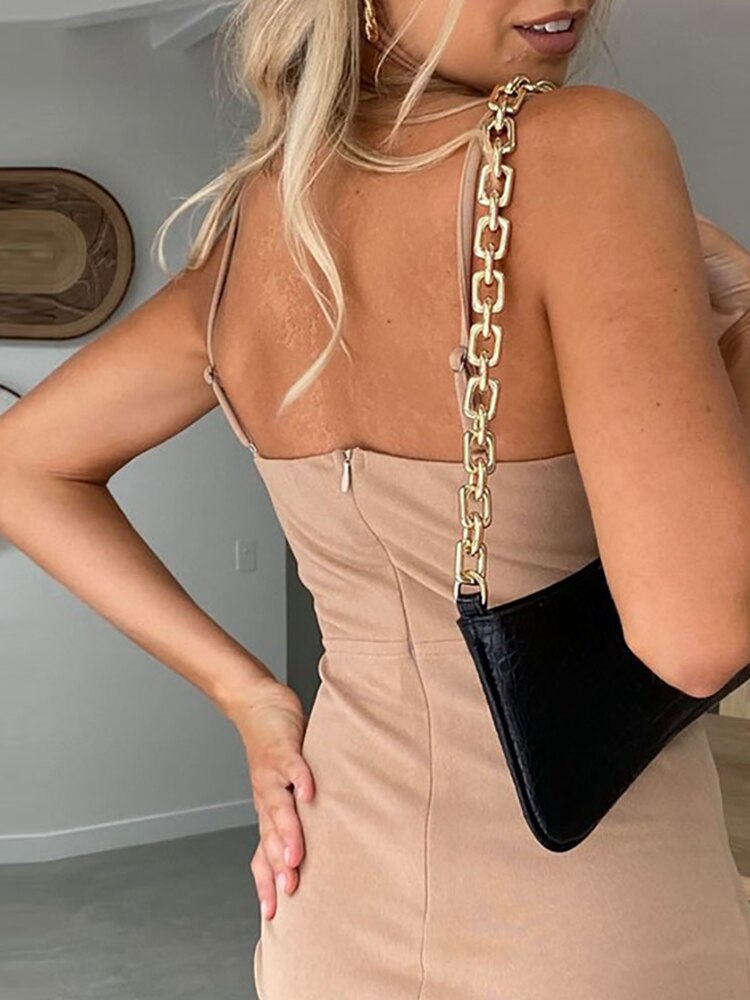 Frau in beigem Kleid mit schwarzer Handtasche und goldener Kette, modisch, elegant, modern.