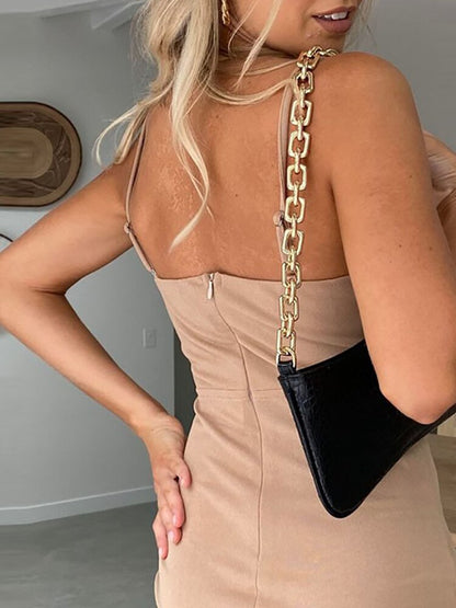 Frau in beigem Kleid mit schwarzer Handtasche und goldener Kette, modisch, elegant, modern.