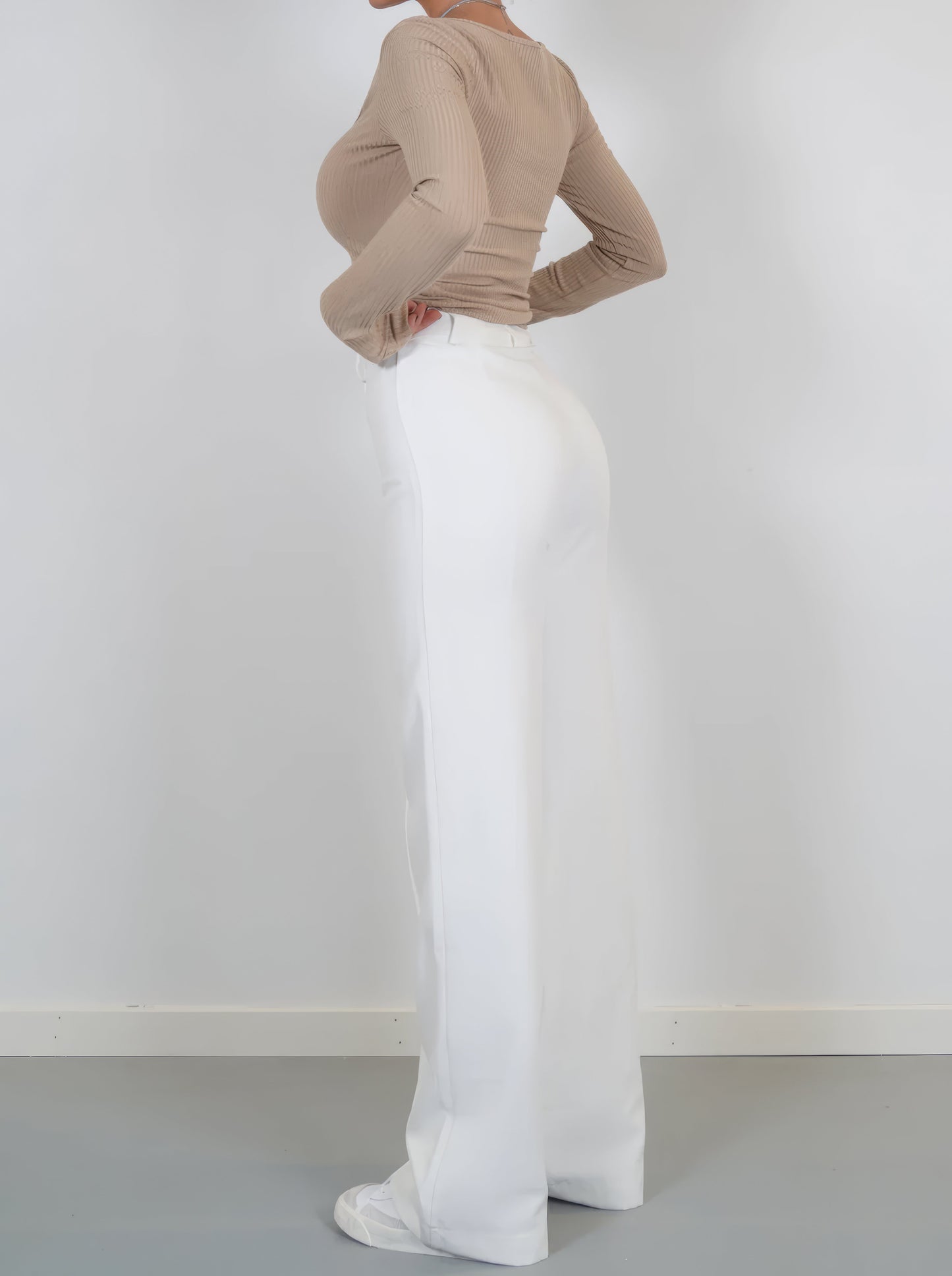 Frau in beigem Langarmshirt und weißer Hose, seitlich, Mode, Damenbekleidung, elegant.