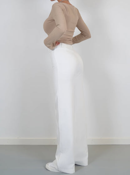 Frau in beigem Langarmshirt und weißer Hose, seitlich, Mode, Damenbekleidung, elegant.