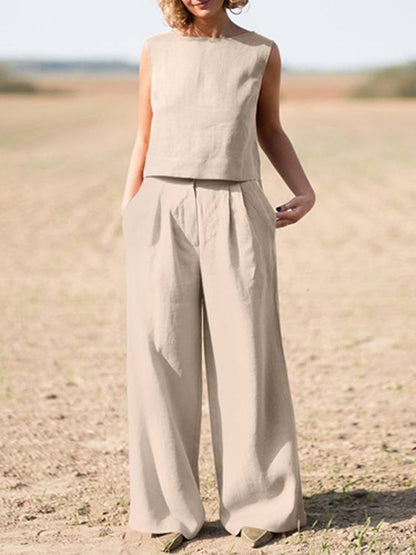 Frau in beigem Leinen-Zweiteiler, ärmelloses Oberteil, weite Hose, Sommermode, Naturhintergrund.