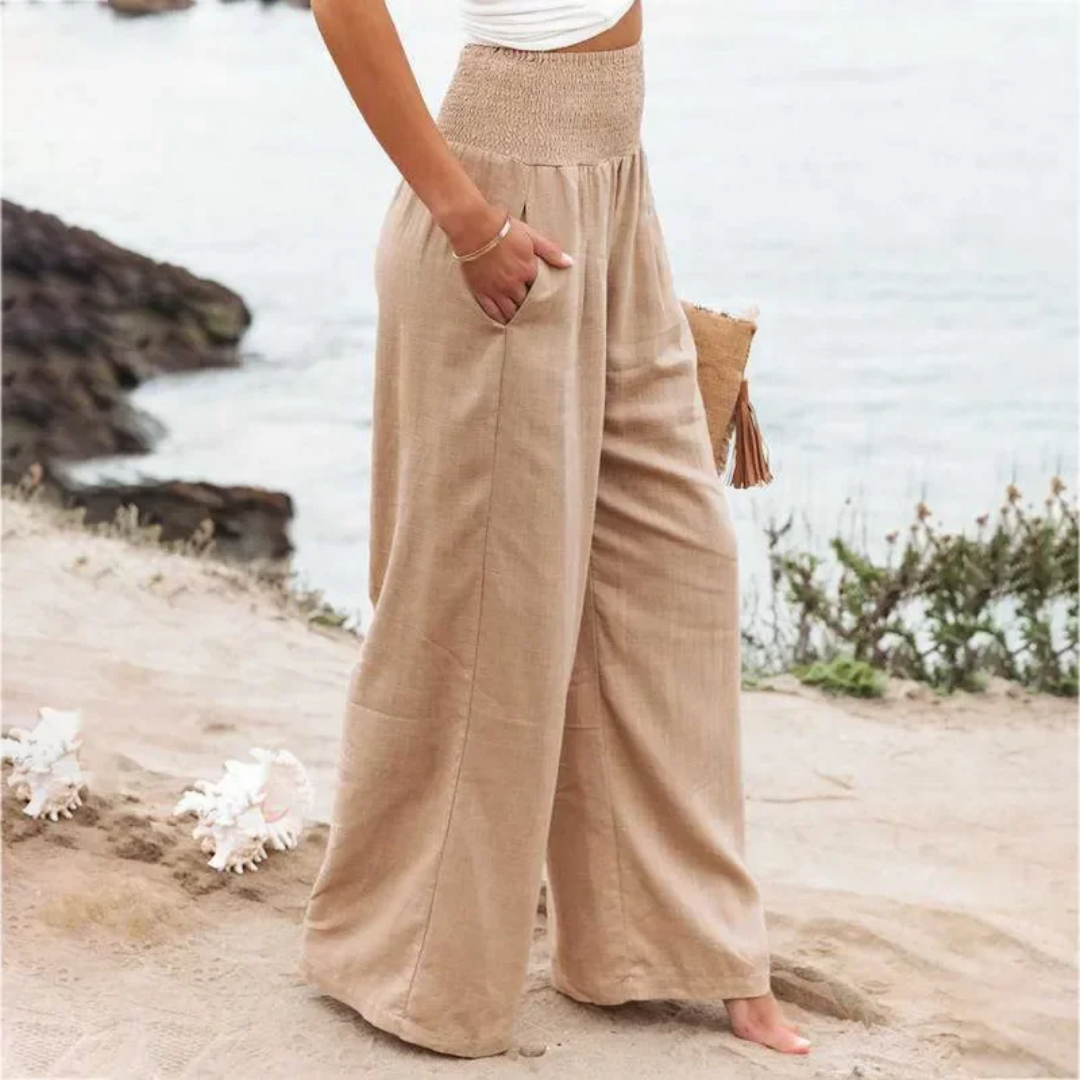 Frau in beigen Leinenhosen am Strand, Sommermode, lässige Damenbekleidung, Boho-Stil.