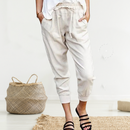 Frau in beigen Leinenhosen, lässiger Stil, Sommermode, mit schwarzen Sandalen.