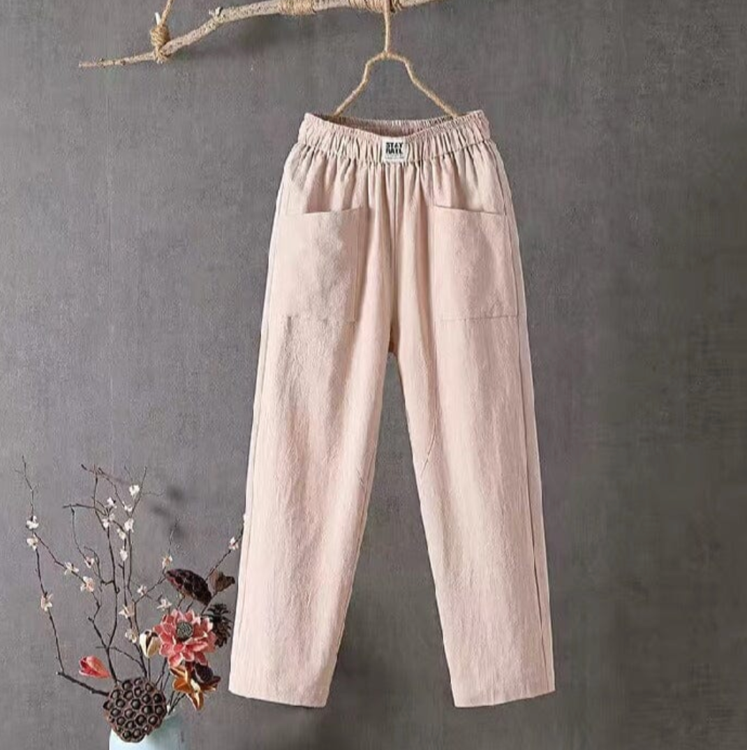 Beige Leinenhose mit elastischem Bund, Damenmode, lässig, bequem, hängend vor grauem Hintergrund.