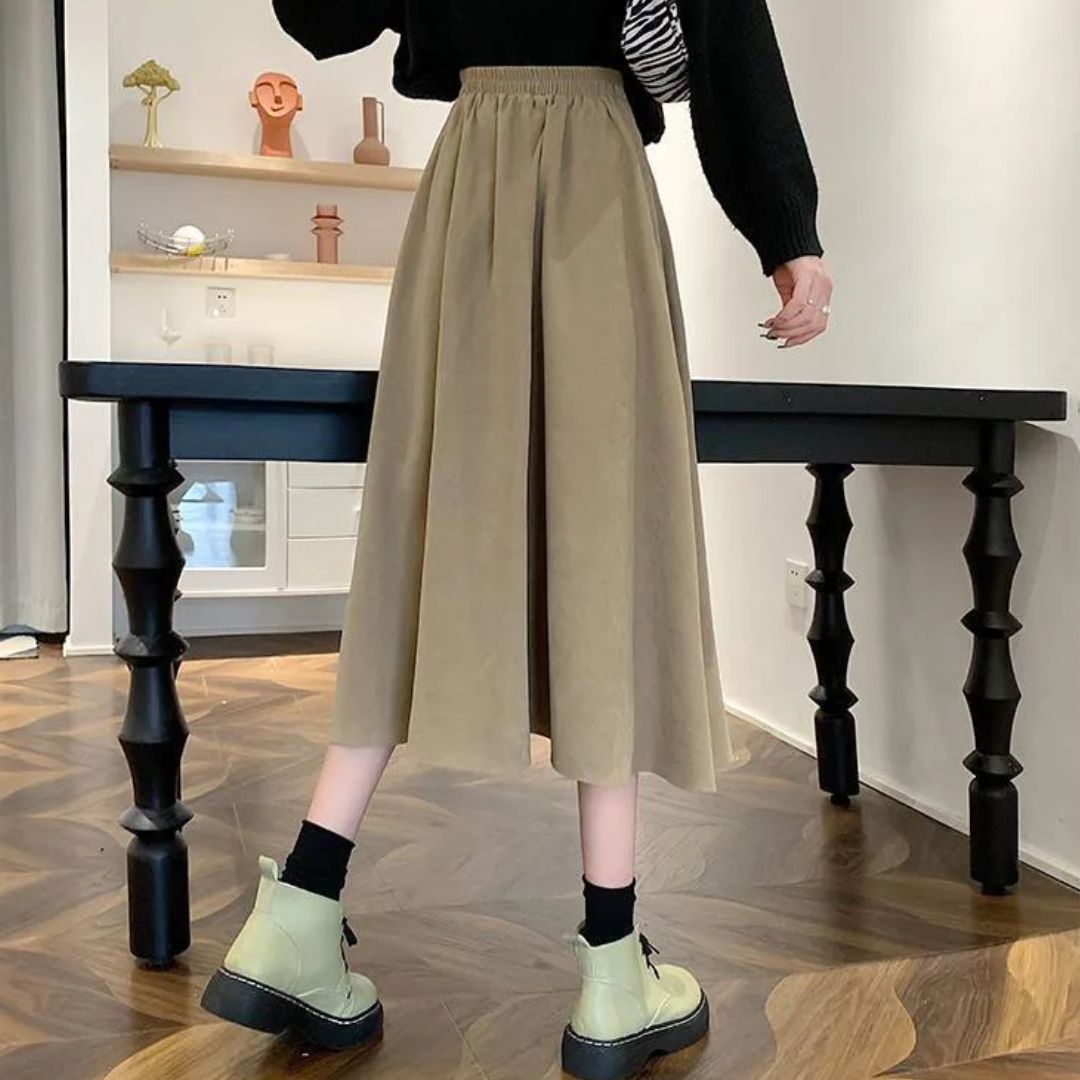 Damenrock beige, knielang, Falten, eleganter Stil, Herbstmode, schwarzer Pullover, Stiefel.