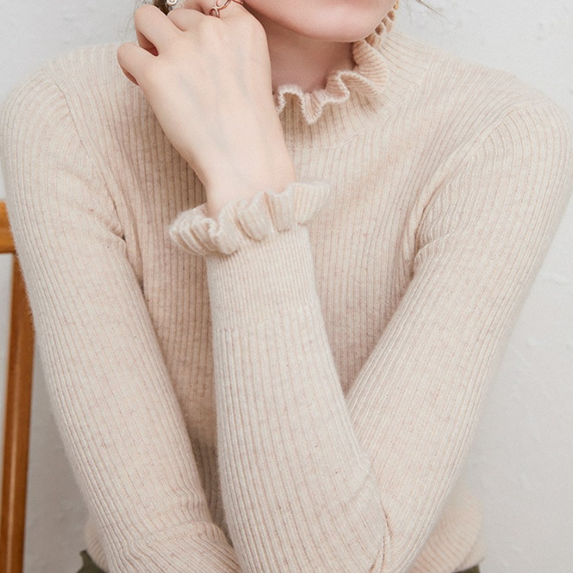 Frau in cremefarbenem Strickpullover mit Rüschenkragen, modisch, elegant, Herbstmode.