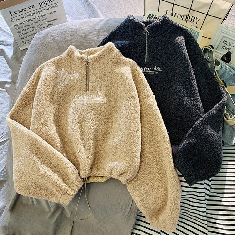 Zwei Fleece-Pullover mit Reißverschluss, beige und schwarz, auf Bett, Schriftzug "California".