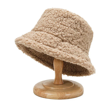 Beiger Damen-Bucket-Hut aus Teddyfell auf Holzständer, modisch und warm.