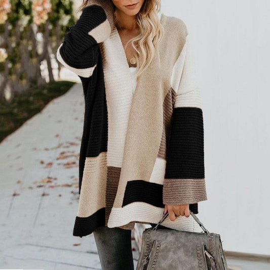 Frau in beige-schwarzem Strickcardigan, hält graue Handtasche, Herbstmode.