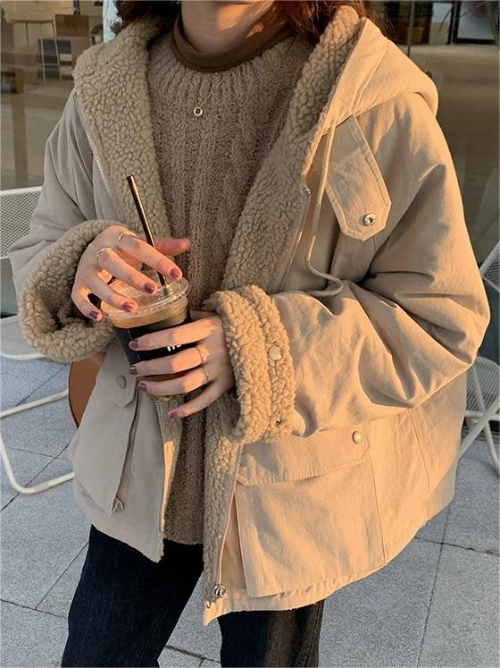 Frau in beiger Teddyjacke mit Kapuze hält Eiskaffee, Wintermode, gemütlicher Stil.