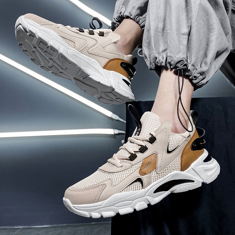 Beige Sneaker mit Mesh-Obermaterial, dicker Sohle und braunen Akzenten für Herren.
