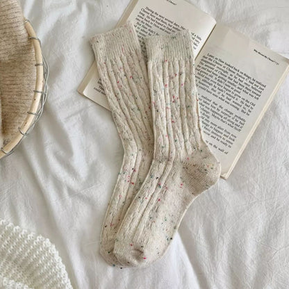 Beige Wollsocken mit bunten Punkten auf offenem Buch, gemütlich, warm, Strickdesign.