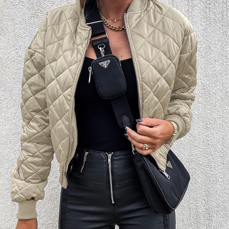 Frau in beiger Steppjacke, schwarzer Hose, mit schwarzer Umhängetasche und Handyhülle.