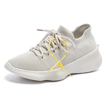 Beiger Sneaker aus Strickmaterial, atmungsaktiv, mit gelbem Akzent, ideal für Freizeit und Sport.