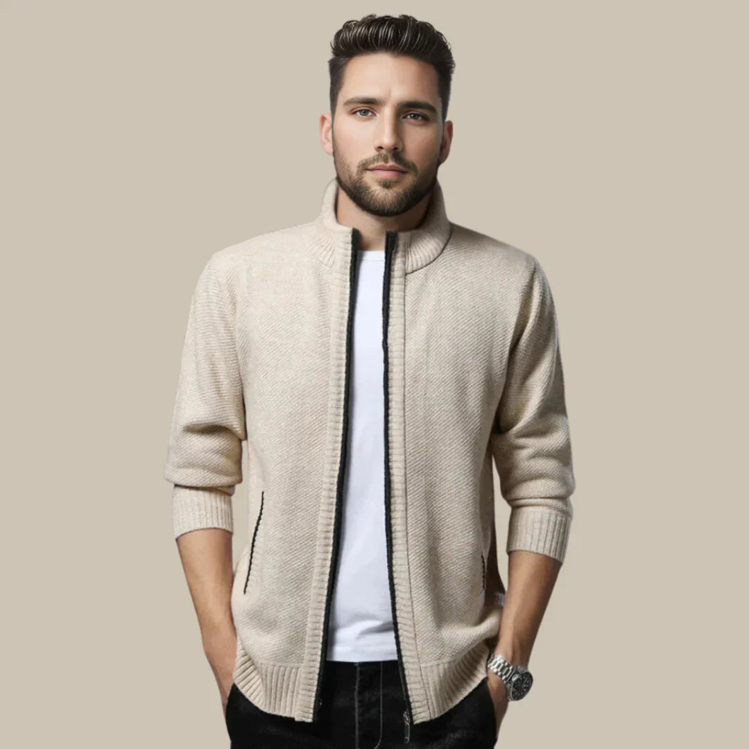 Mann in beigem Strickjacke, weißem T-Shirt, schwarzer Hose; modische Herrenbekleidung.