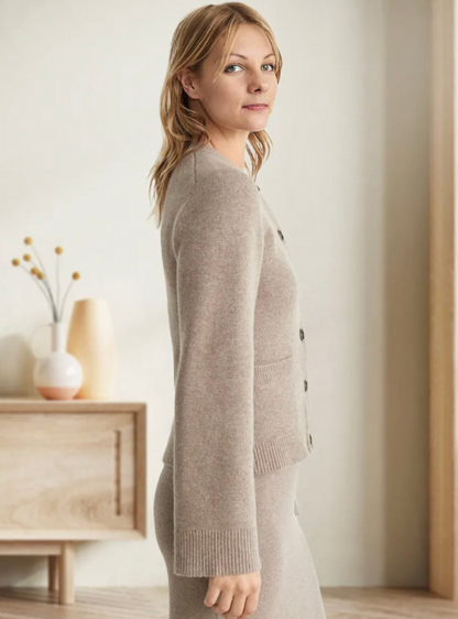 Frau trägt beige Strickjacke mit Knöpfen, weiches Material, elegantes Design, Innenraum.