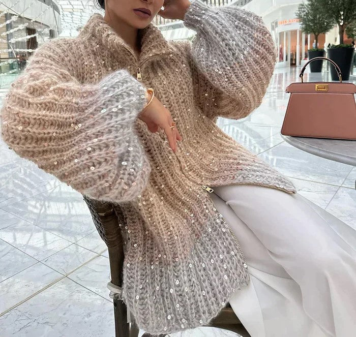 Frau in beigem Strickpullover mit Pailletten, sitzt in modernem Einkaufszentrum.