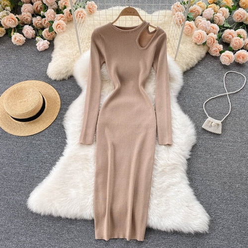 Beiges Strickkleid mit asymmetrischem Ausschnitt, langärmelig, elegant, auf weißem Fellteppich.