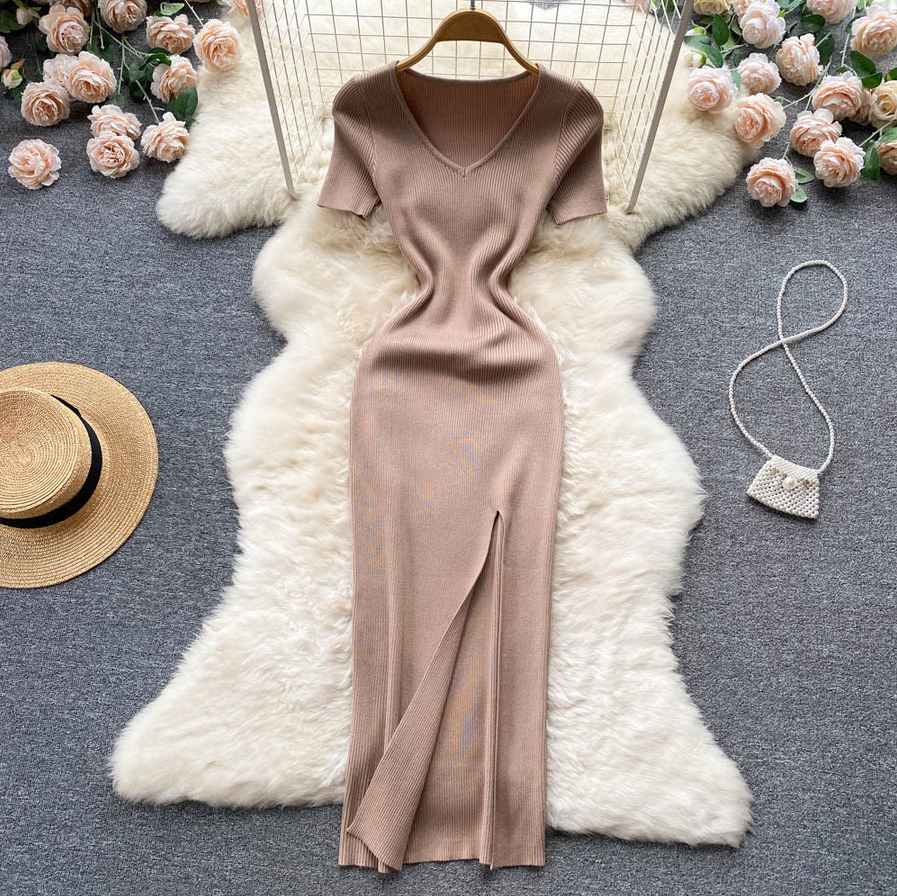 Beiges Strickkleid mit V-Ausschnitt, Kurzarm, Schlitz, auf weißem Fell, umgeben von Rosen.