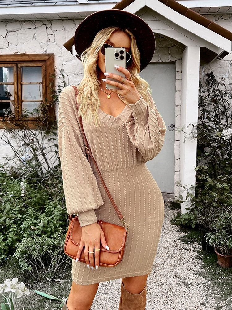 Frau in beigem Strickkleid mit Hut und brauner Tasche vor Haus, Mode Herbst Outfit.