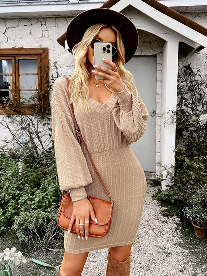 Frau in beigem Strickkleid mit Hut und brauner Tasche vor Haus, Mode Herbst Outfit.