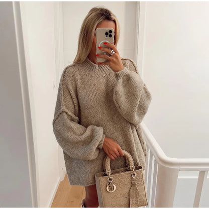 Frau in beigem Oversize-Pullover mit beiger Designer-Handtasche, Selfie im modernen Flur.