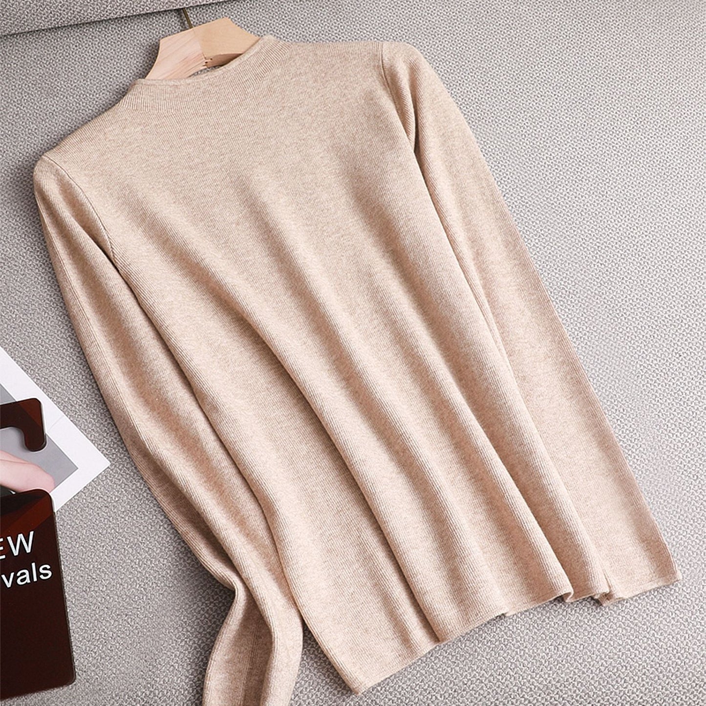 Beiger Damenpullover aus Kaschmir, langärmelig, elegant, weich, auf grauem Hintergrund.