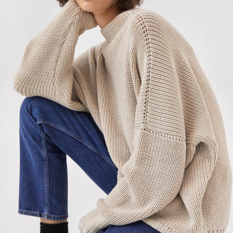 Frau in beigem Strickpullover und blauer Jeans, lässige Mode, Herbstkleidung, gemütlicher Look.