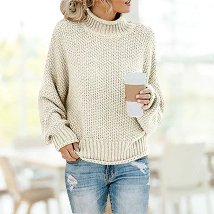 Frau in cremefarbenem Strickpullover mit Kaffeebecher, lässige Herbstmode, gemütlich.