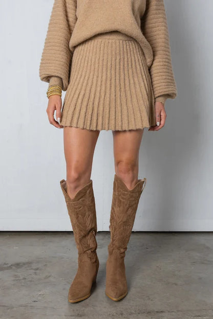Frau in beigem Strickkleid und Stiefeln, modisches Herbstoutfit, gemütlicher Look.